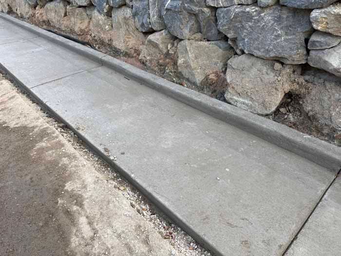 Concrete gutter along a stone wall.