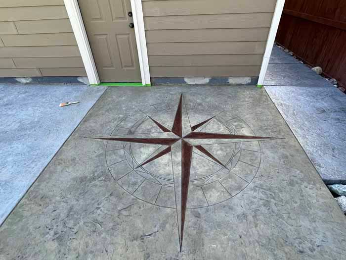 Concrete patio with a compass rose design in brown.