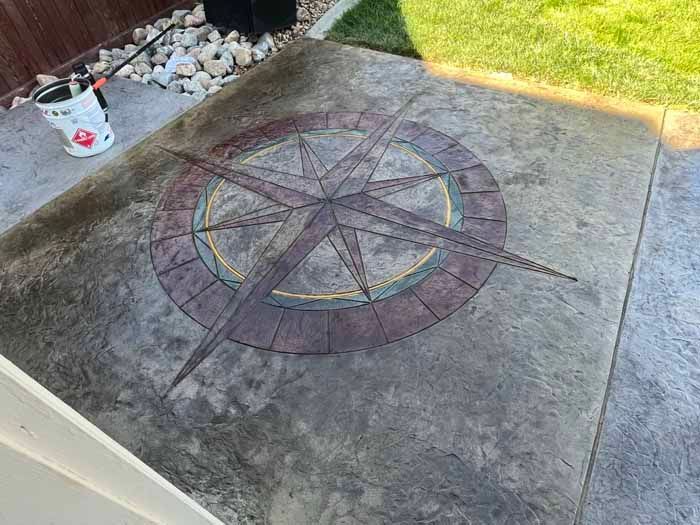 Concrete patio with a compass rose design in brown and gold.