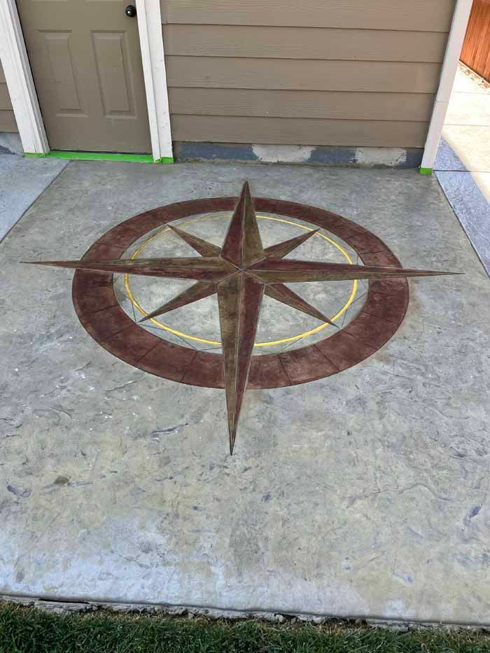 Concrete patio with a compass rose design in brown and yellow.