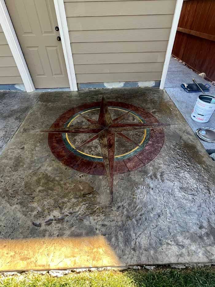 Concrete patio with a compass rose design in red, gold, and brown.