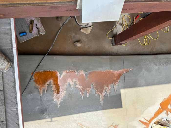 Construction in progress: Grey wall with a painted landscape. Orange, brown, and white colors used. Tools and beams visible.