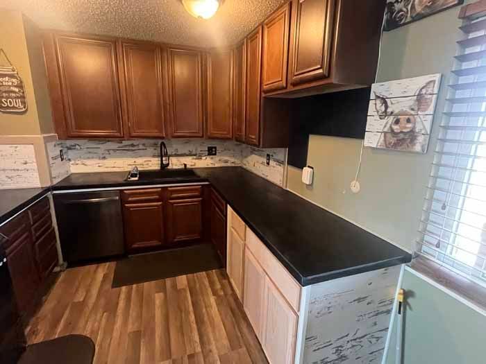 Kitchen with dark countertops, brown cabinets, stainless steel appliances, and wood floors.