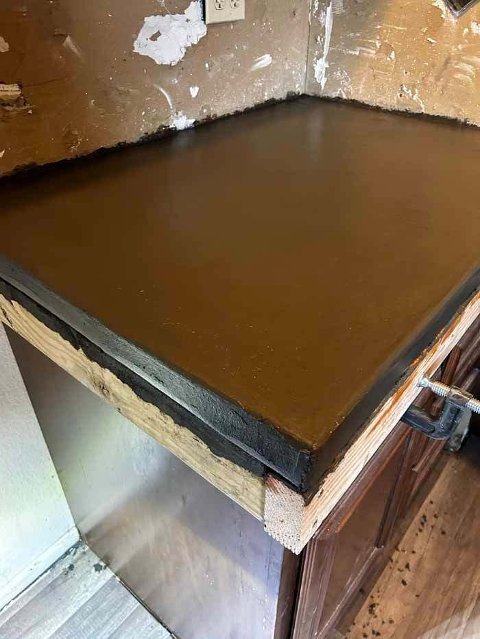 Brown countertop with black edge over a wooden cabinet. The countertop has a smooth, glossy finish.