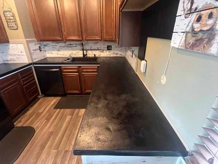 Kitchen with dark countertops, wooden cabinets, and white backsplash.