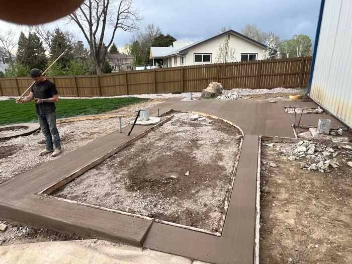 Man smoothing fresh concrete path and patio in yard with wooden forms.