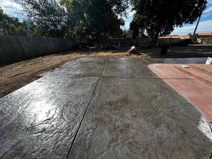 Stamped concrete patio, dark gray, with a textured finish, in a backyard setting.