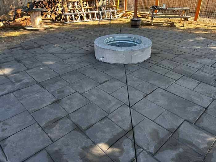Concrete patio with a circular fire pit in the center.