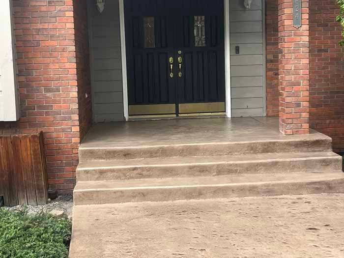 Brick and grey home entry with concrete steps leading to double doors.