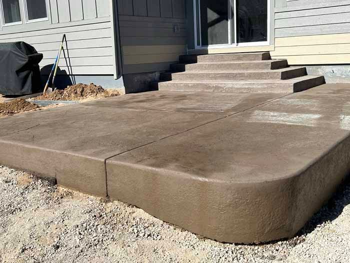 Concrete patio with steps leading to a house, brown hue.