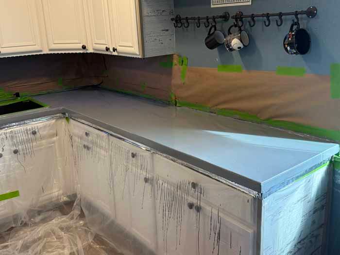 Kitchen with gray countertops, white cabinets, and protective coverings.