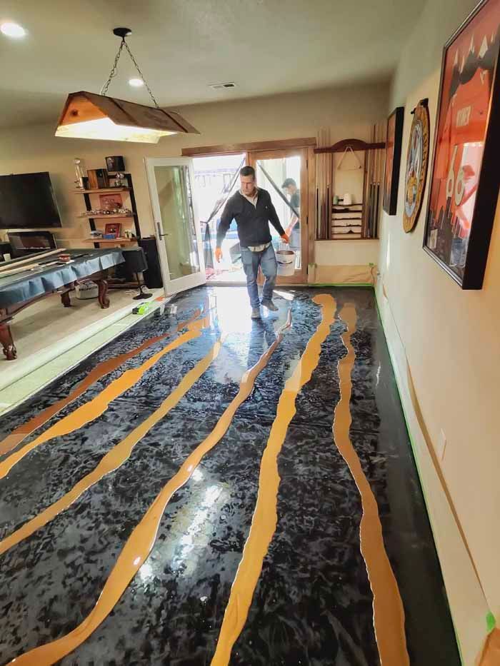 Man walking on a metallic black and gold epoxy floor with doorway in the background.