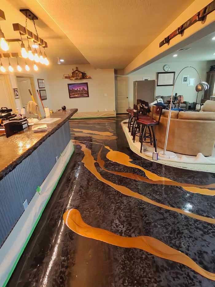 Epoxy floor installation in progress; black floor with gold swirls. A bar and seating are visible.