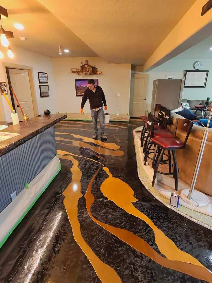 Person stands on a decorative floor with brown and gold swirls in a room with a bar, furniture, and a painting.