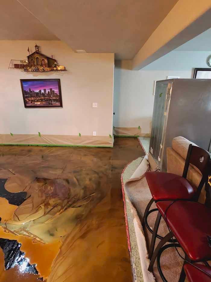 Room with epoxy floor in shades of brown, gold, and black; bar stools and artwork on wall.