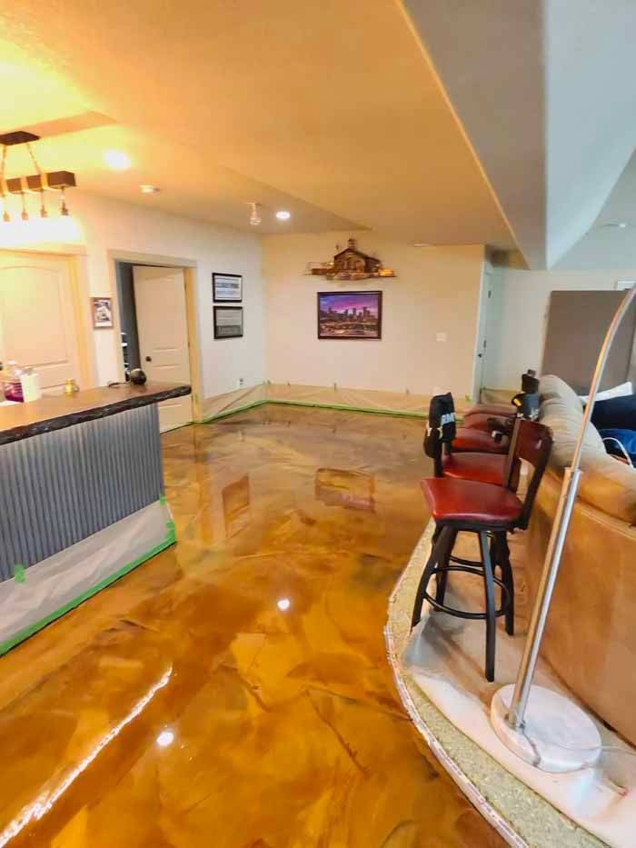 Shiny gold epoxy floor in a room with a bar, stools, and artwork.