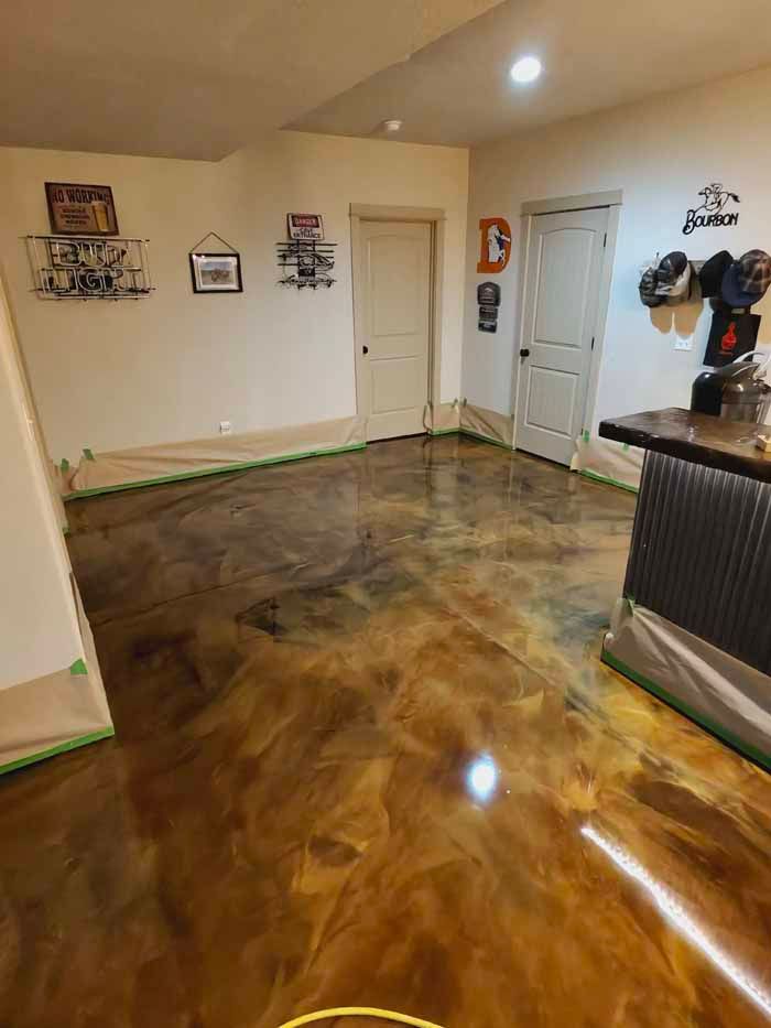 Metallic epoxy floor in a basement room with various wall decorations and doors.