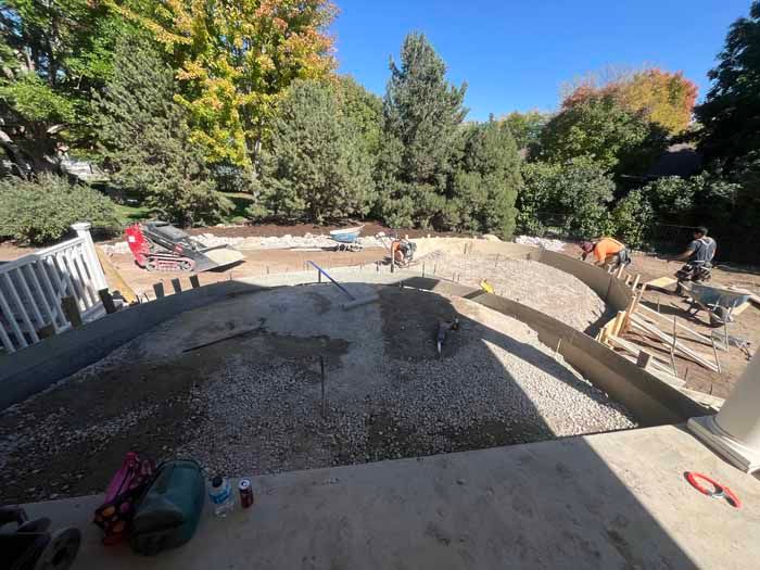 Construction site with workers, gravel, and forms. Outdoors on a sunny day.
