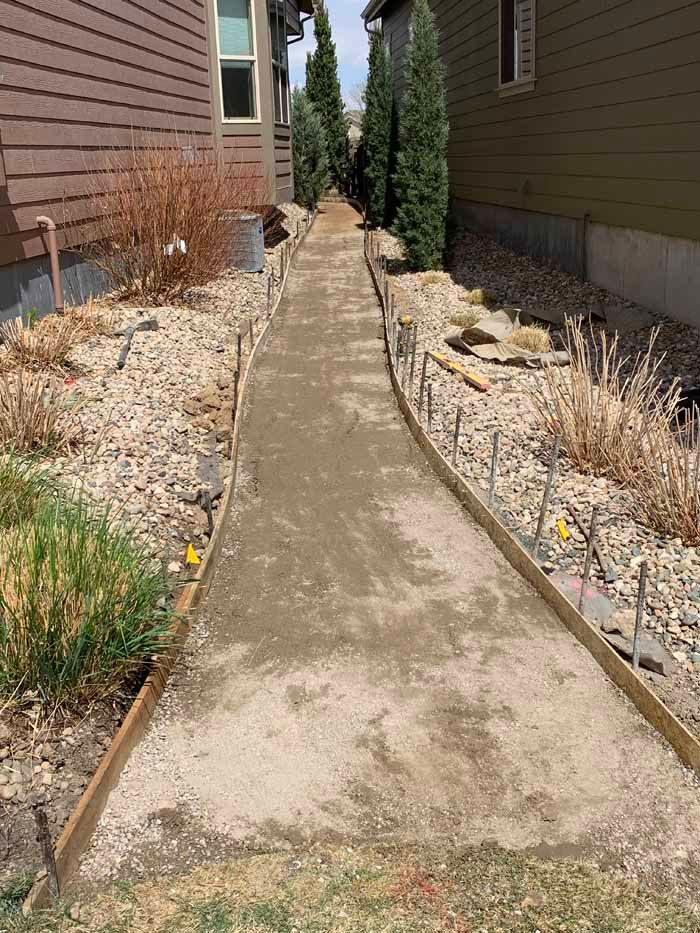 Concrete pathway under construction between two houses.