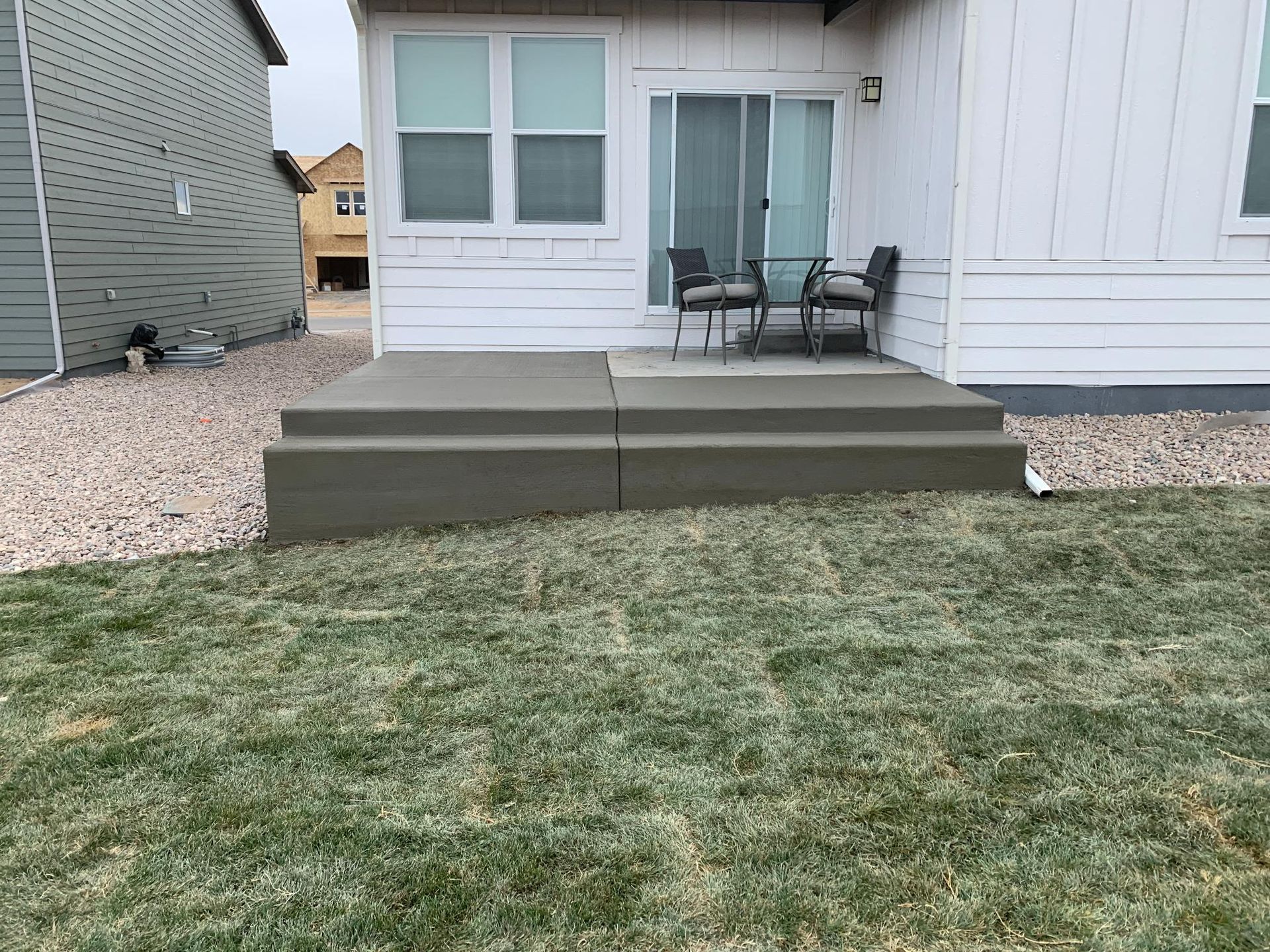 Concrete steps leading up to a house with a sliding glass door and patio furniture.