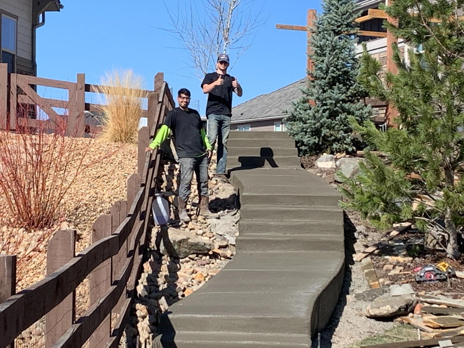 Two men stand on newly poured concrete stairs outdoors.