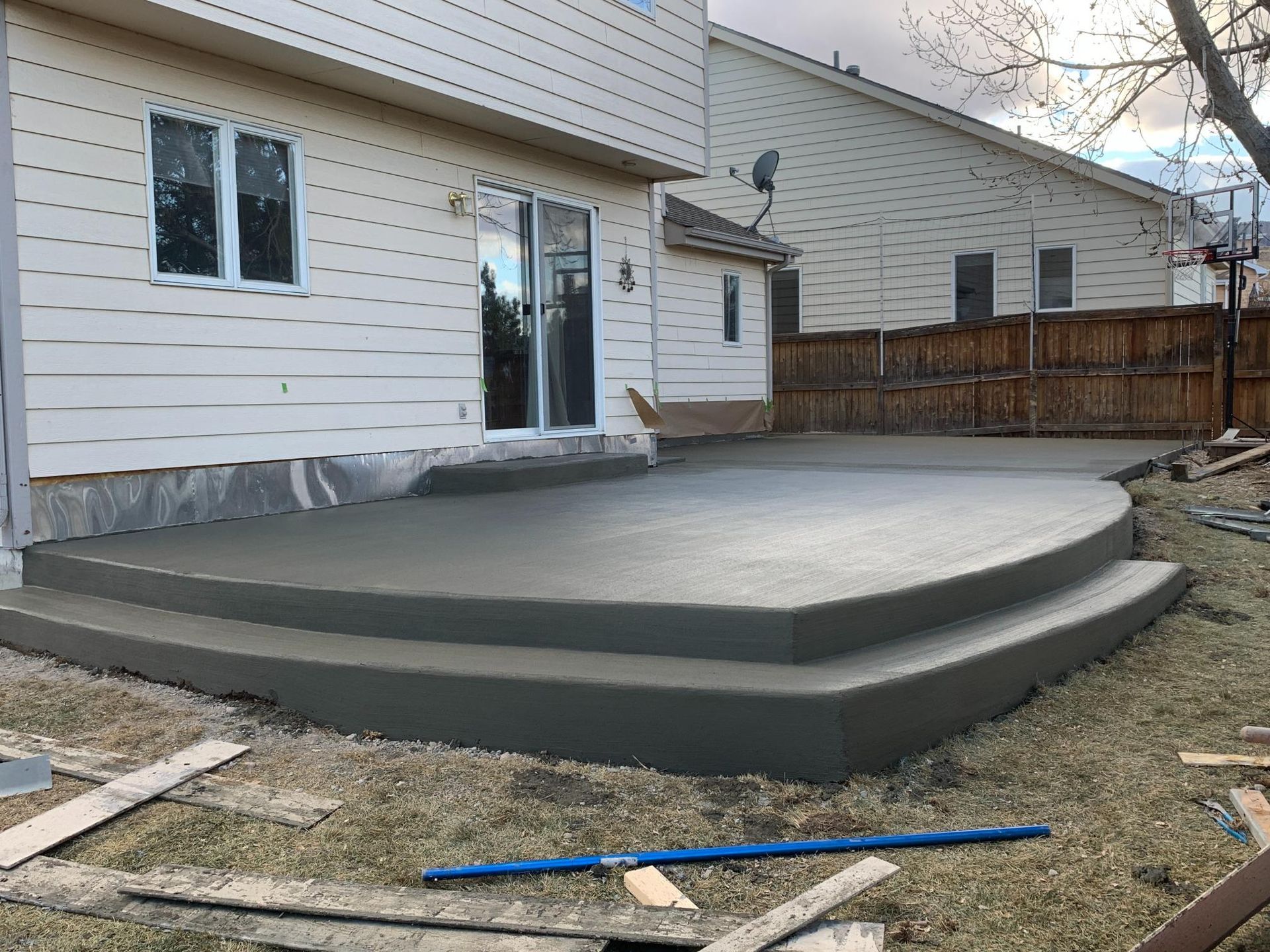 Newly poured concrete patio with steps in a backyard.