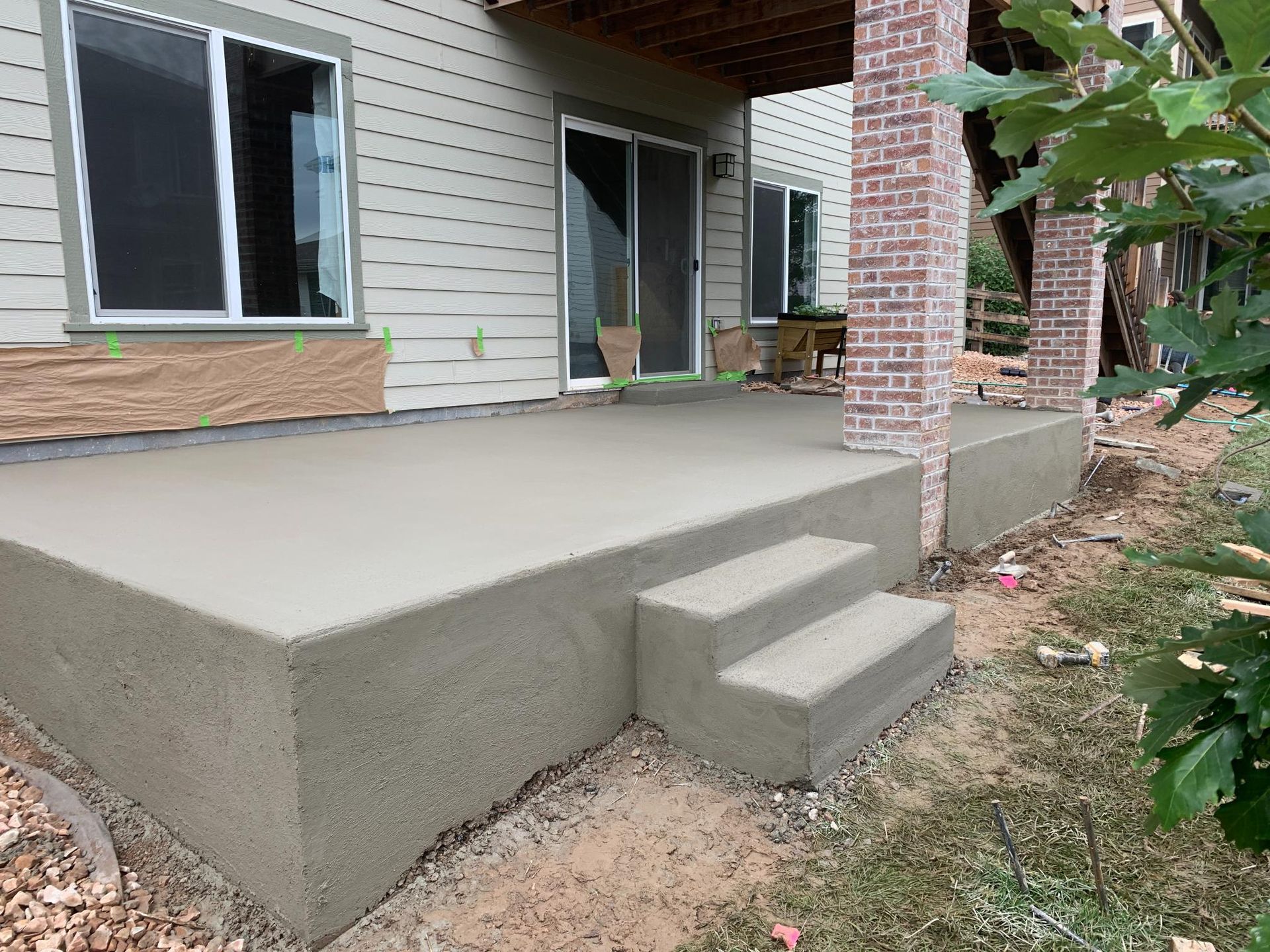 Concrete patio with steps, next to a house with windows and a sliding glass door.
