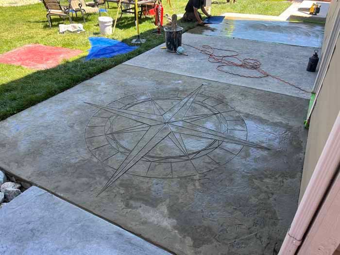 Concrete patio with compass rose design being worked on by a person.