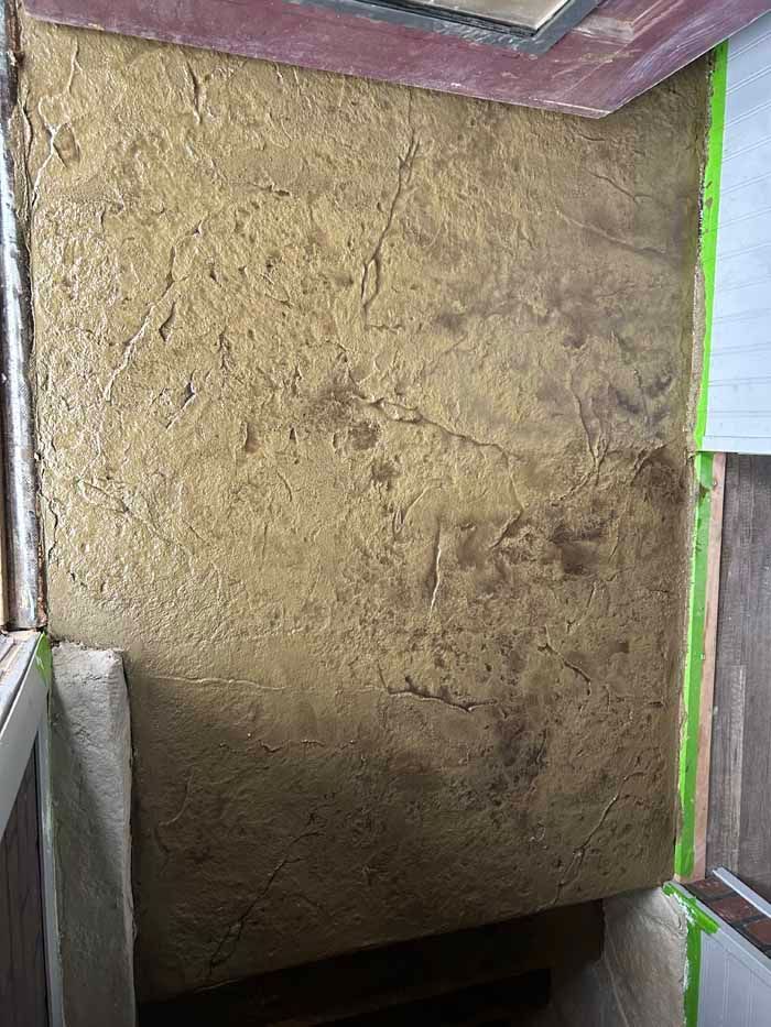 Textured gold wall with brown accents, viewed in a room with a wooden frame.
