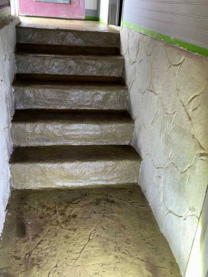 Concrete steps and wall with textured finish, lit from the bottom.