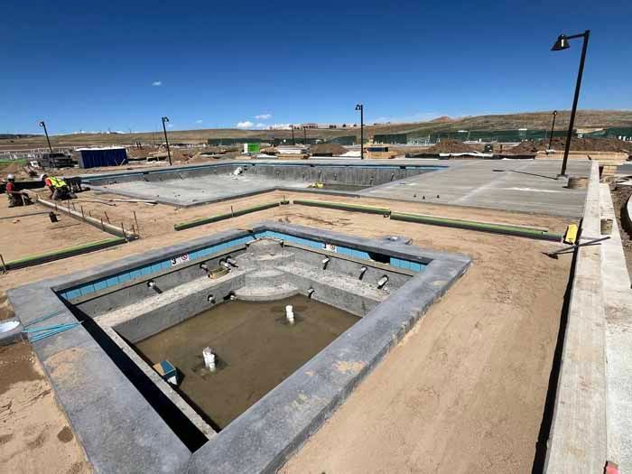 Construction site with multiple empty swimming pools, concrete, blue sky.