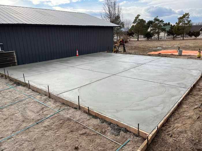 Newly poured concrete slab with a building in the background and a person working on the surface.