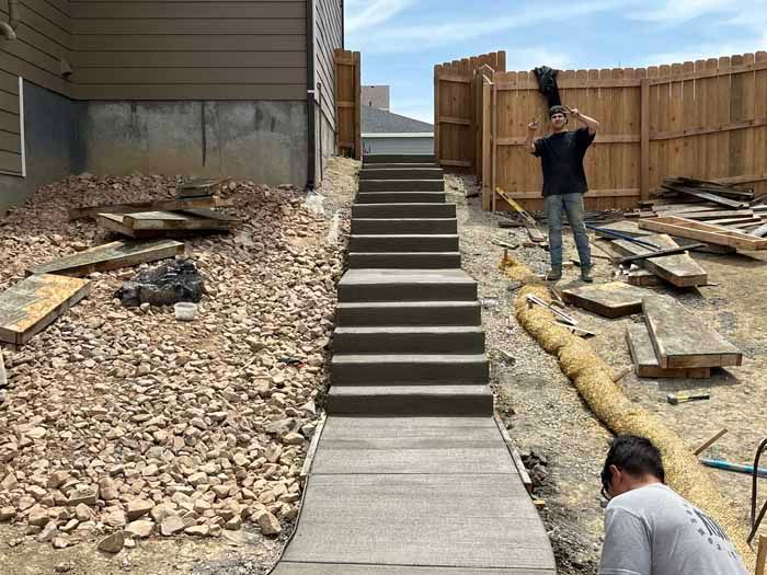 Newly constructed concrete steps and walkway leading uphill with workers present.