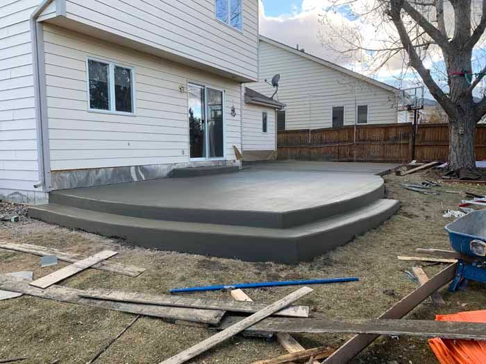 Newly poured concrete patio with two steps in a backyard.