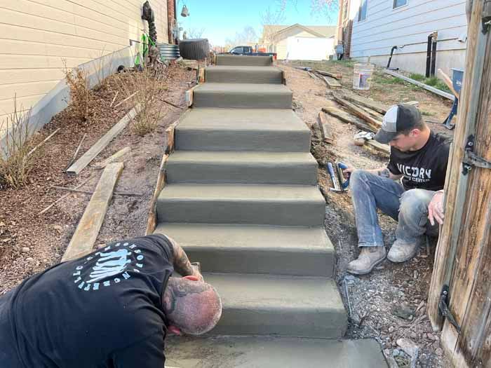 Two people working on new concrete stairs. Construction site, outdoors.