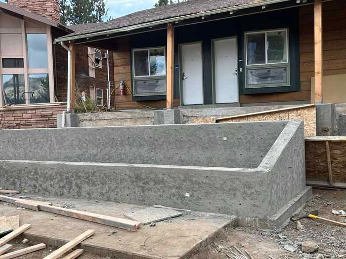 Exterior view of a building under construction, featuring newly poured concrete steps and foundation.