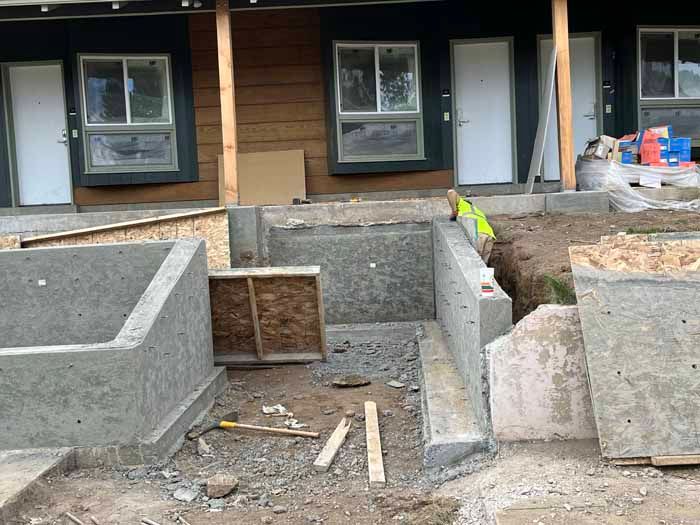 Construction site with concrete structures in front of a building with white doors and windows.