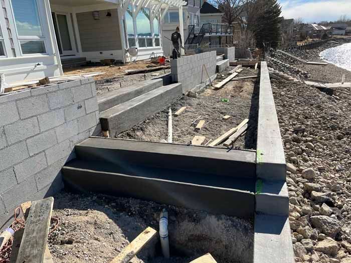Construction of concrete steps and retaining walls near a waterfront.