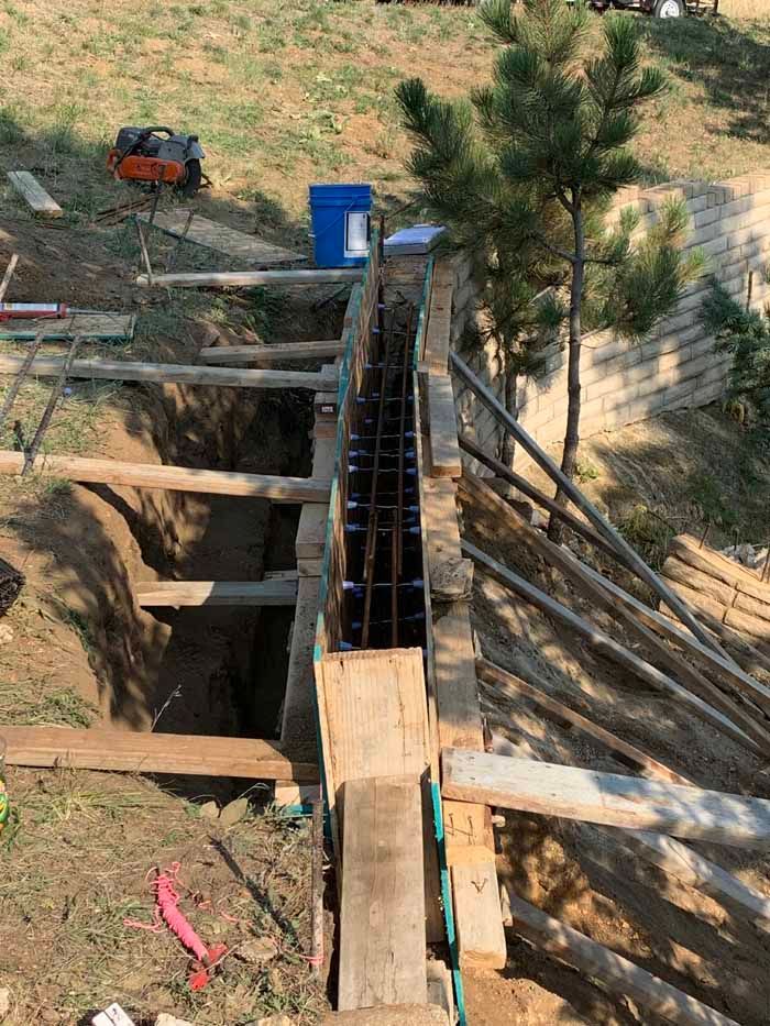 Construction site with wooden forms and rebar for a retaining wall.