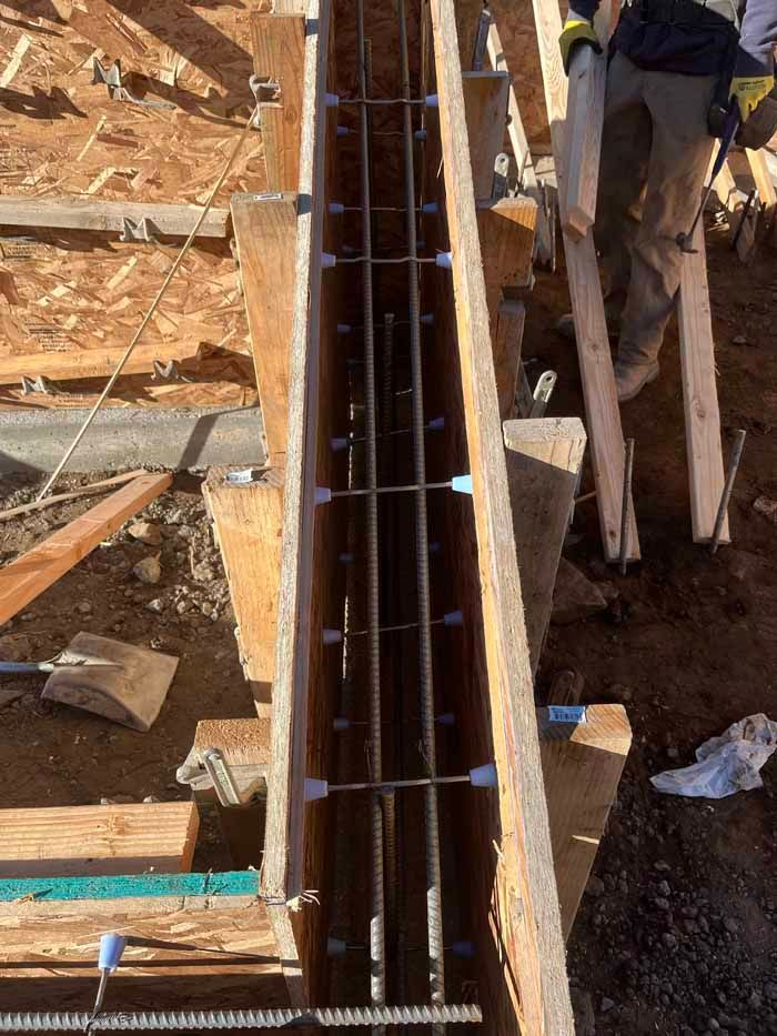 Wooden formwork with steel rebar, ready for concrete pouring. Construction worker visible.