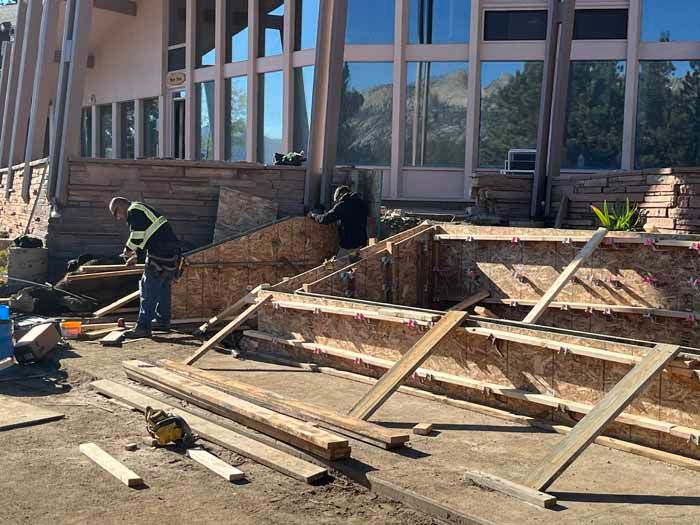 Construction workers building steps in front of a building with large windows.