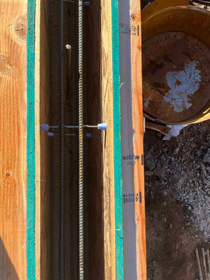 Wooden formwork with steel rebar reinforcement, spacers, and partial concrete, for a concrete column.