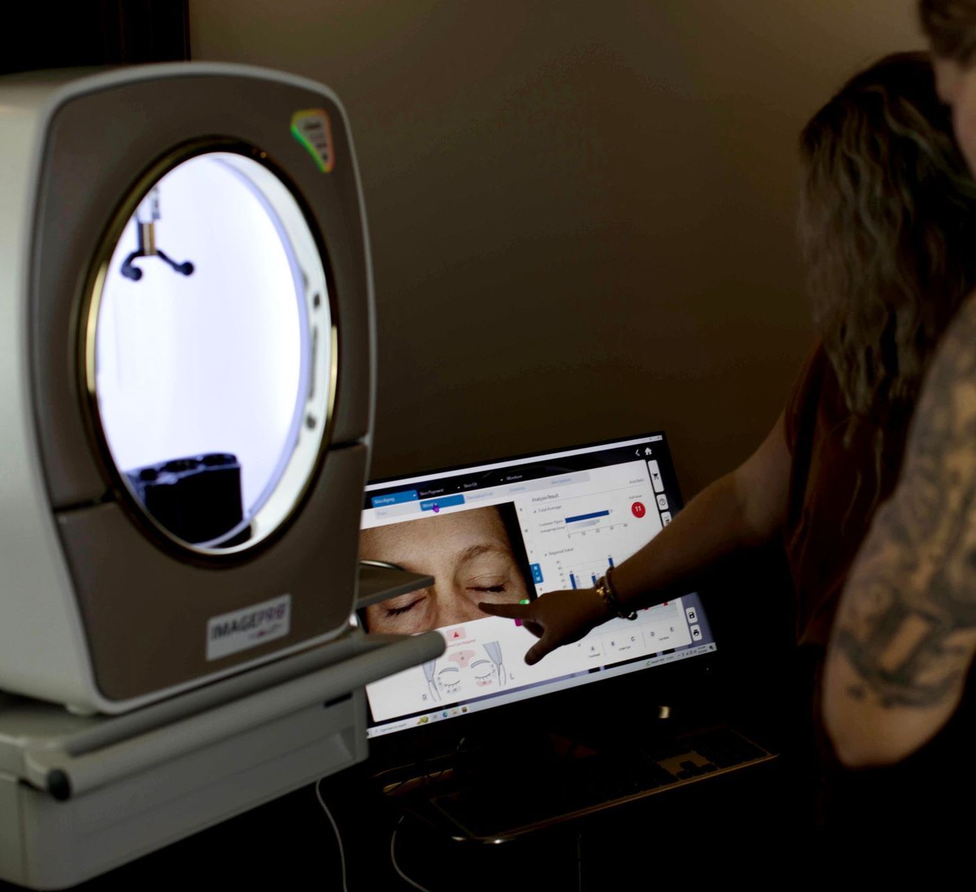 A woman is pointing at a computer screen with a woman 's face on it