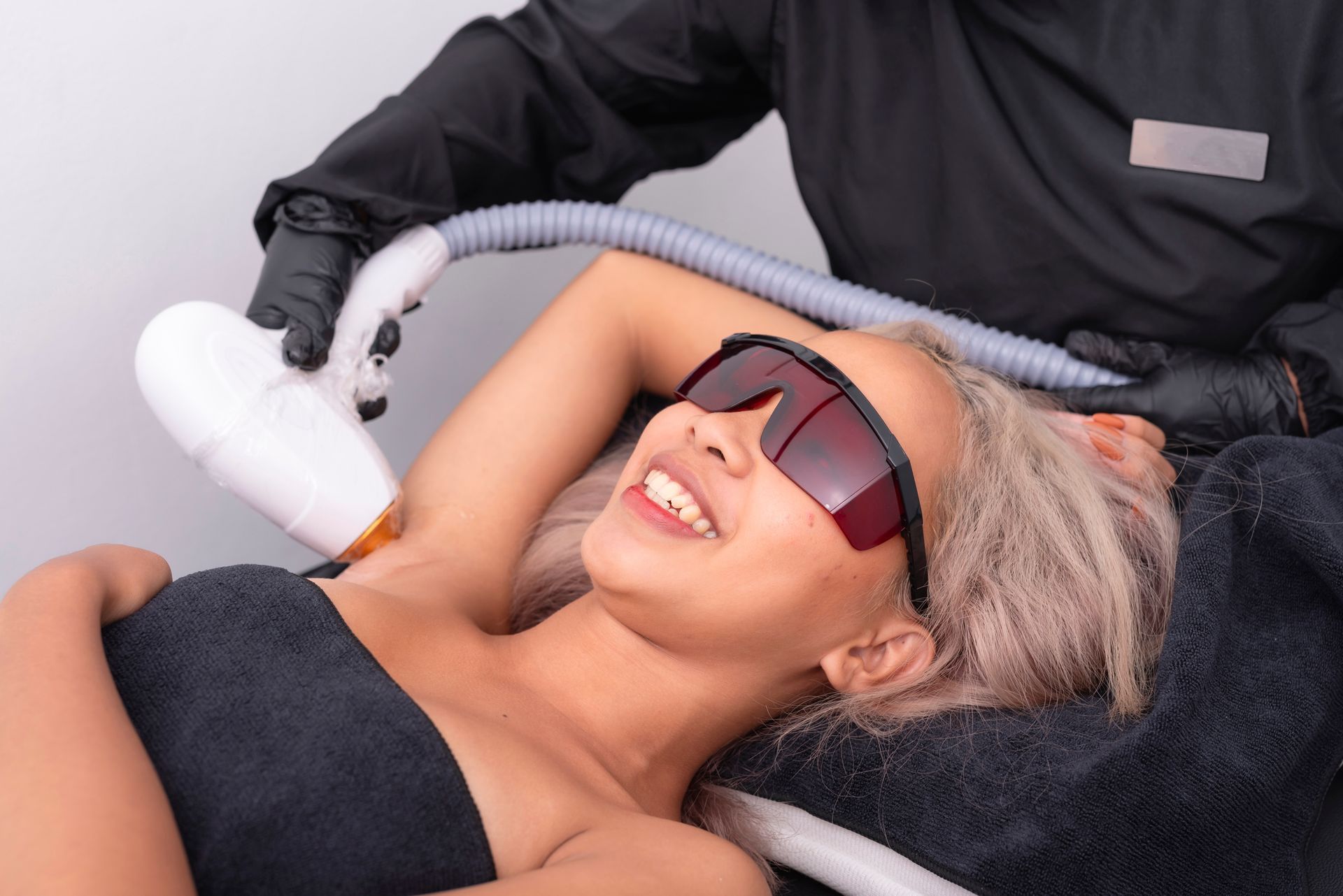 A woman is getting a laser hair removal treatment on her armpit.