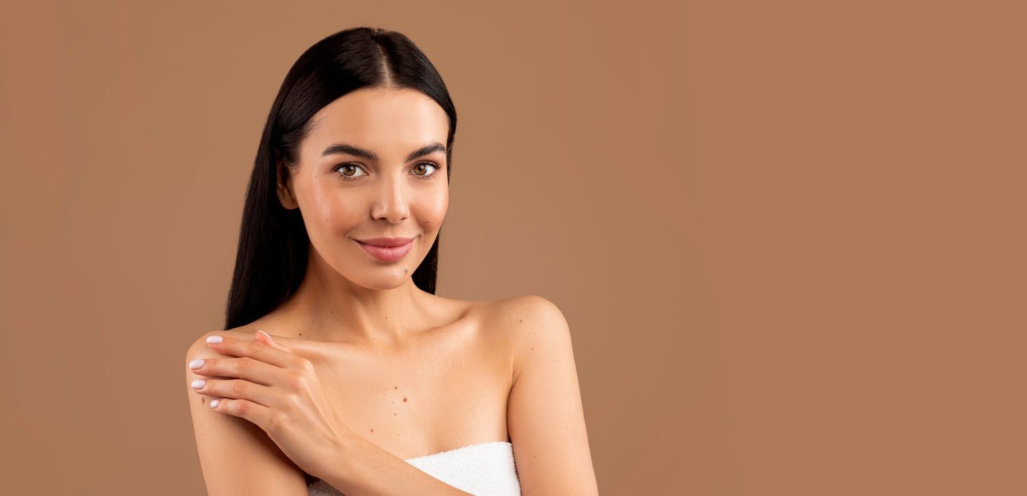 A woman wrapped in a towel is touching her shoulder.