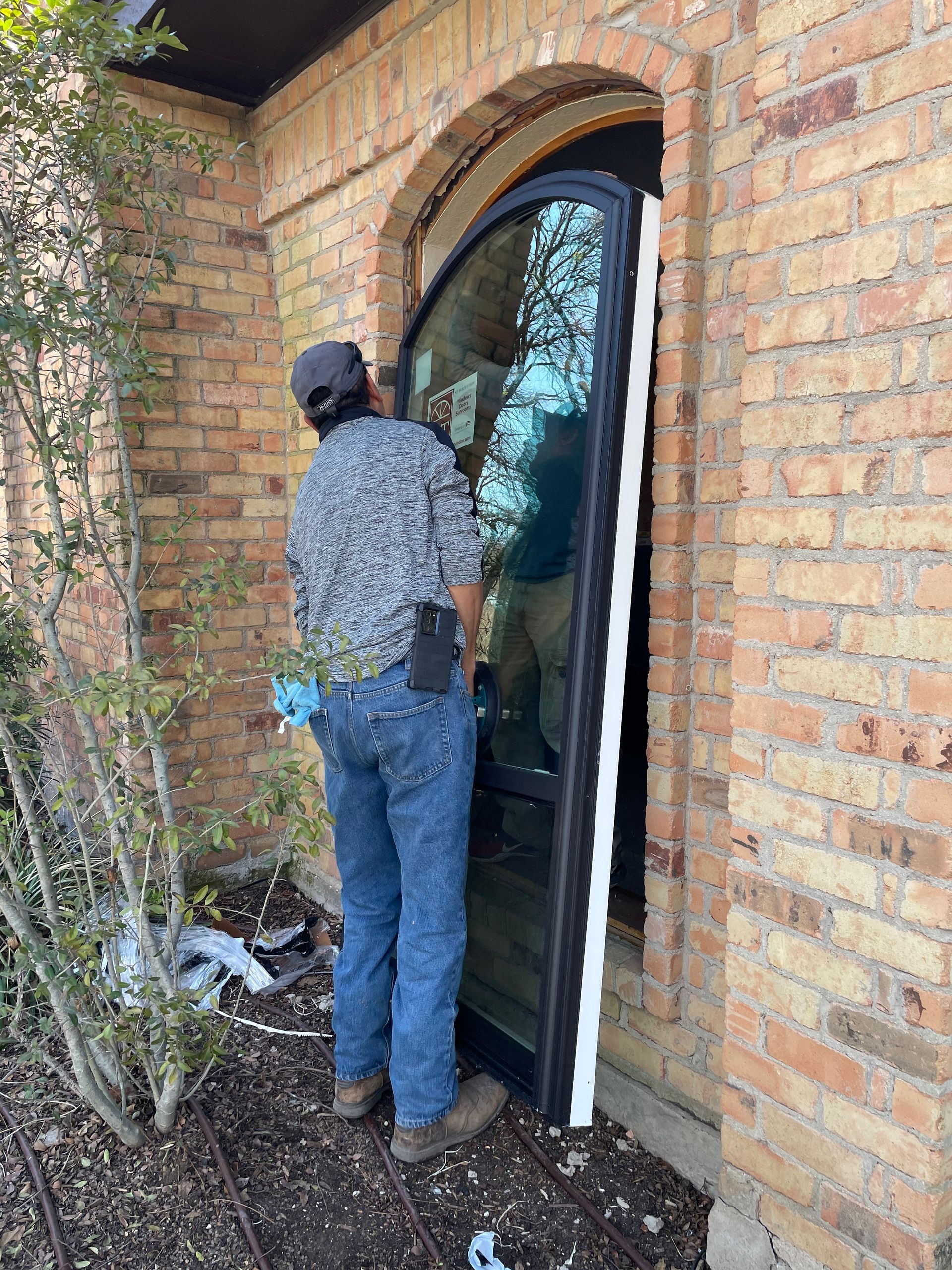 A man is installing a glass door in a brick building.