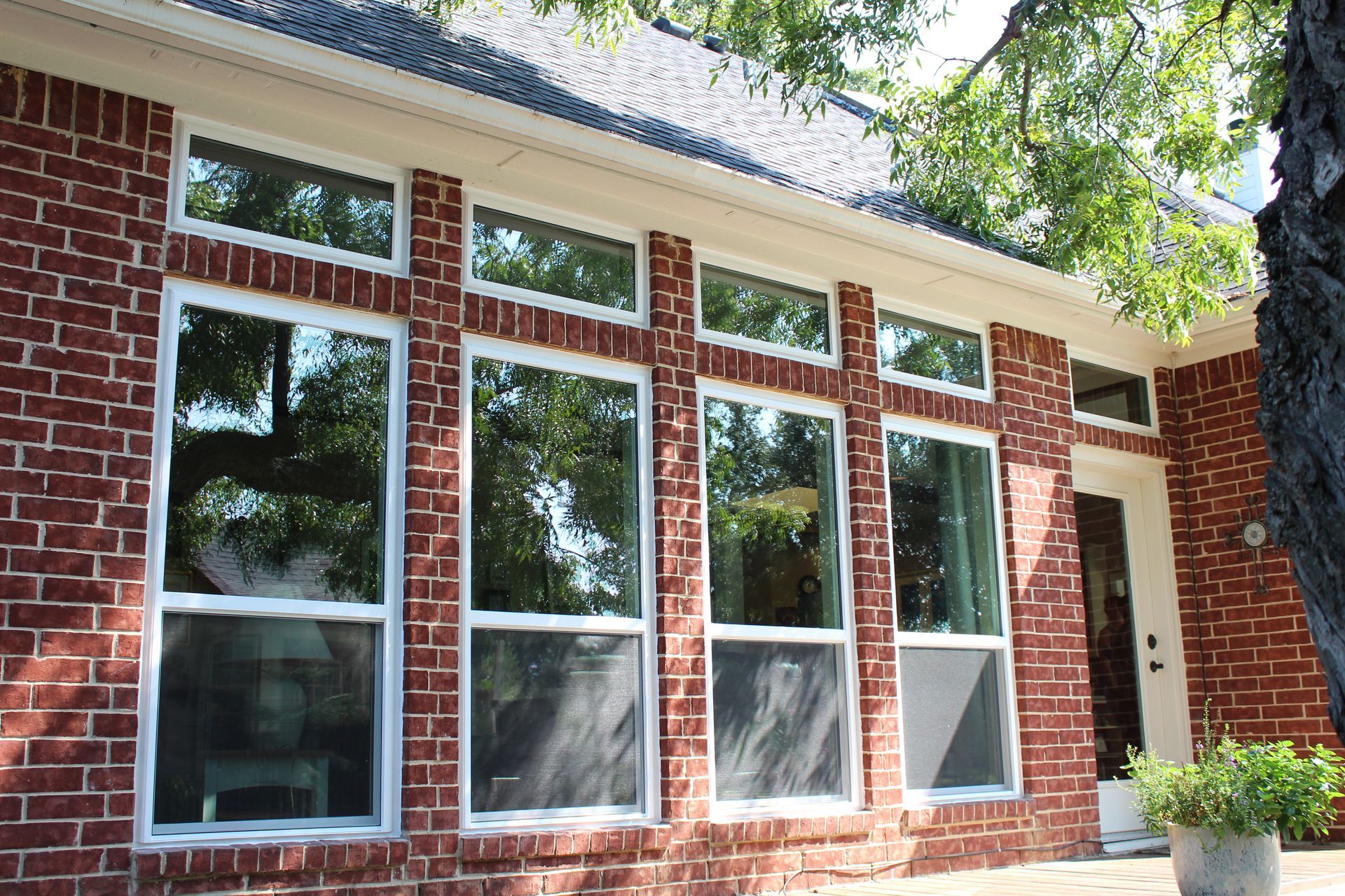 A brick house with lots of windows and a tree in front of it