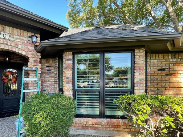 A ladder is sitting in front of a brick house.