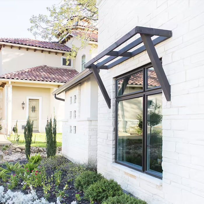 A white brick building with a window with a canopy over it