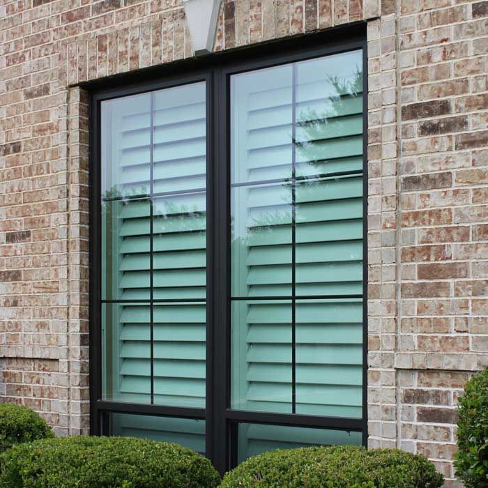 A brick building with a window with shutters on it